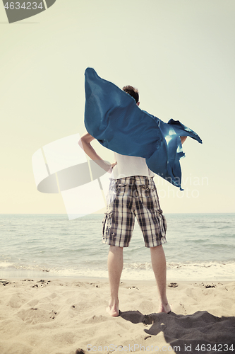 Image of funny superhero standing on beach