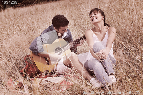 Image of happy couple enjoying countryside picnic in long grass