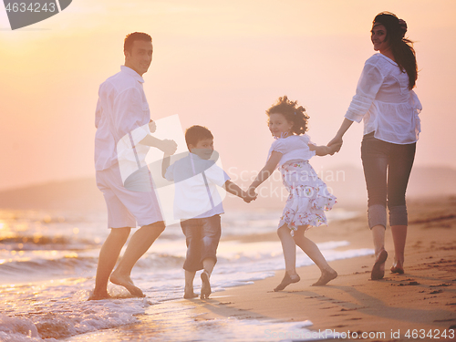Image of happy young family have fun on beach at sunset