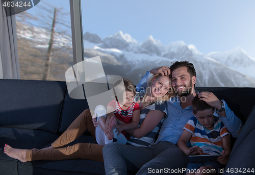 Image of happy young couple spending time with kids at home