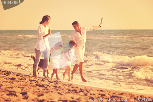 Image of happy family playing with dog on beach