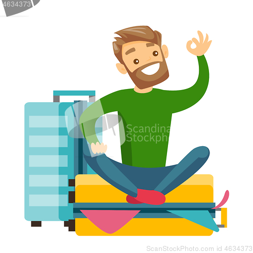 Image of Young caucasian white man sitting on suitcase.