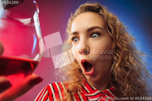 Image of The surprised young woman in party clothes posing with glass of wine.