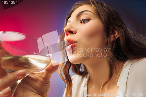 Image of The surprised young woman in party clothes posing with glass of wine.