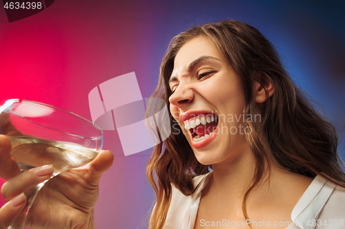 Image of The sad young woman in party clothes posing with glass of wine.