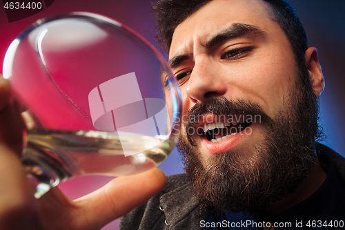 Image of The surprised young man posing with glass of wine.