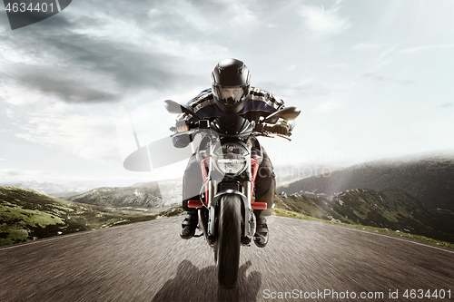 Image of biker on mountain highway, riding around a curve with a motion blur toned with a retro vintage instagram filter app or action