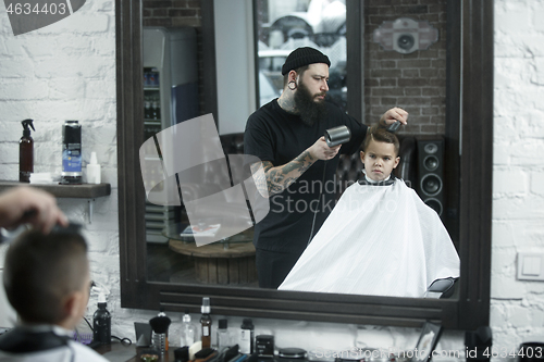 Image of Children hairdresser cutting little boy against a dark background.