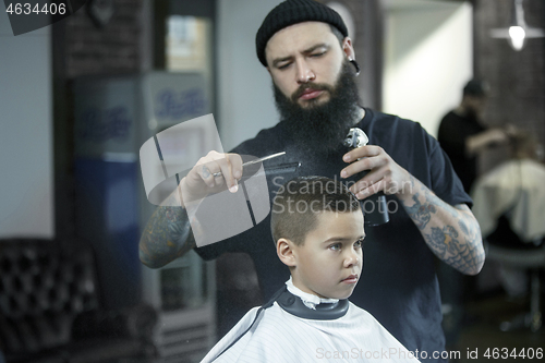 Image of Children hairdresser cutting little boy against a dark background.