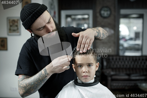 Image of Children hairdresser cutting little boy against a dark background.