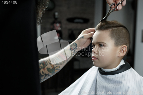 Image of Children hairdresser cutting little boy against a dark background.