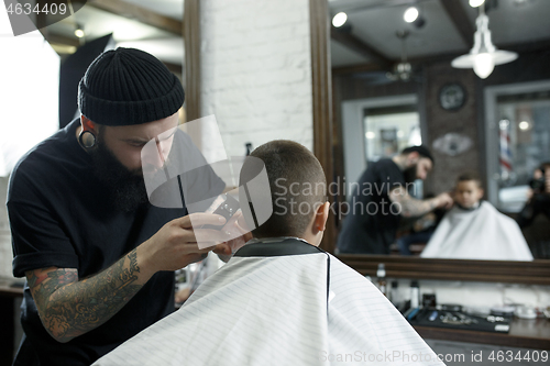 Image of Children hairdresser cutting little boy against a dark background.