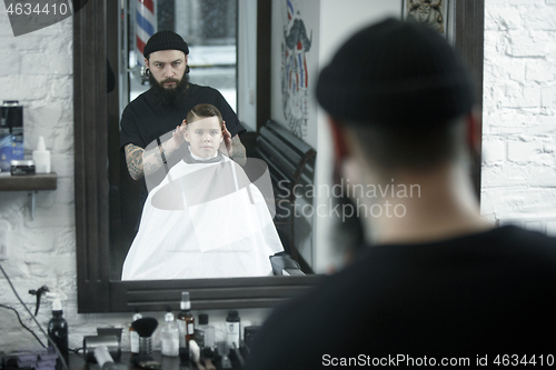 Image of Children hairdresser cutting little boy against a dark background.