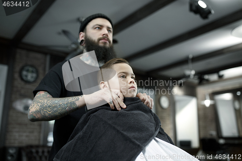 Image of Children hairdresser cutting little boy against a dark background.