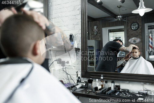 Image of Children hairdresser cutting little boy against a dark background.