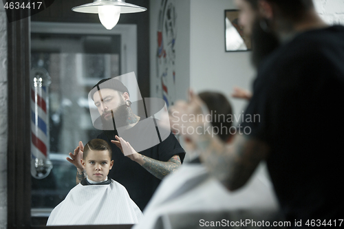 Image of Children hairdresser cutting little boy against a dark background.