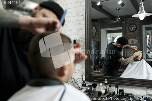 Image of Children hairdresser cutting little boy against a dark background.