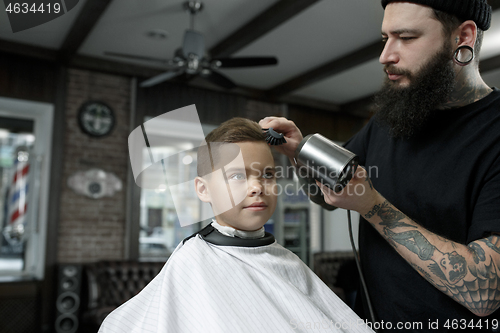 Image of Children hairdresser cutting little boy against a dark background.