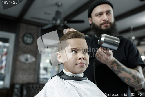 Image of Children hairdresser cutting little boy against a dark background.