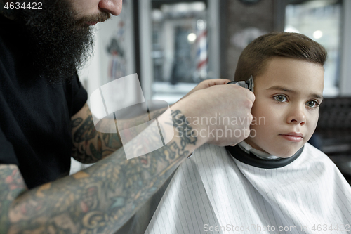 Image of Children hairdresser cutting little boy against a dark background.