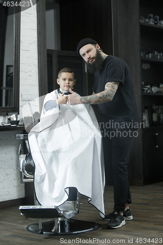 Image of Children hairdresser cutting little boy against a dark background.