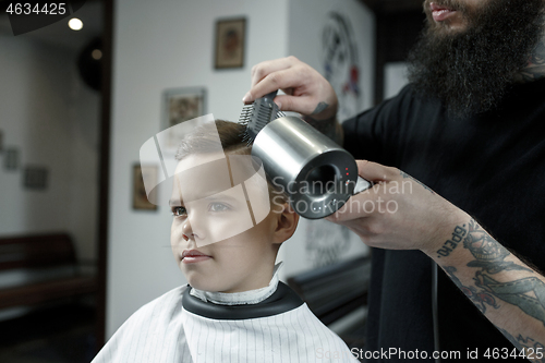 Image of Children hairdresser cutting little boy against a dark background.