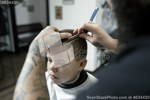 Image of Children hairdresser cutting little boy against a dark background.