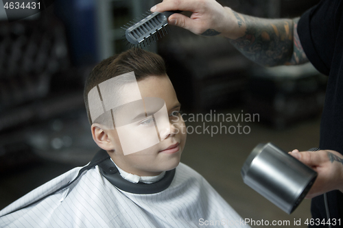 Image of Children hairdresser cutting little boy against a dark background.