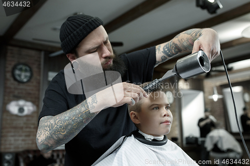 Image of Children hairdresser cutting little boy against a dark background.