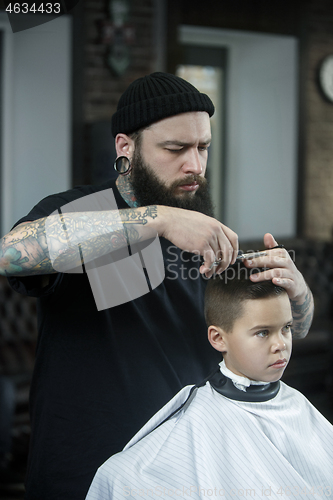 Image of Children hairdresser cutting little boy against a dark background.