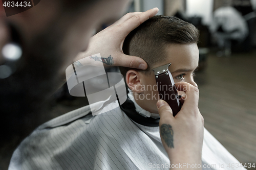 Image of Children hairdresser cutting little boy against a dark background.