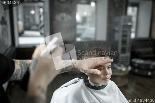 Image of Children hairdresser cutting little boy against a dark background.