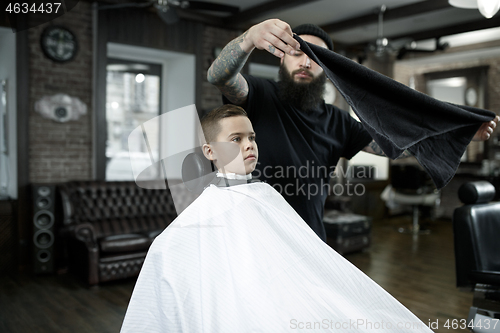 Image of Children hairdresser cutting little boy against a dark background.