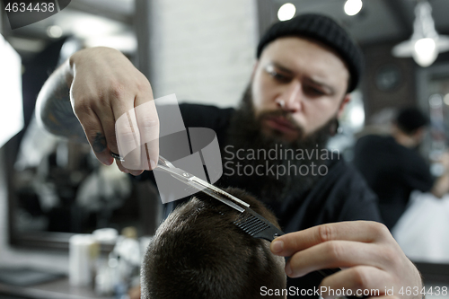 Image of Children hairdresser cutting little boy against a dark background.