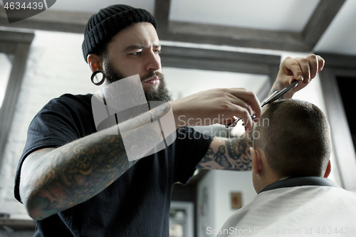 Image of Children hairdresser cutting little boy against a dark background.