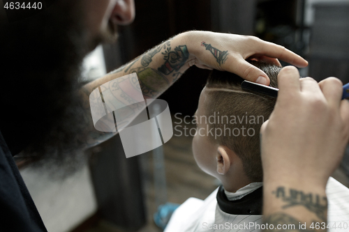 Image of Children hairdresser cutting little boy against a dark background.