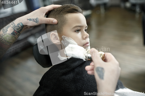 Image of Children hairdresser cutting little boy against a dark background.