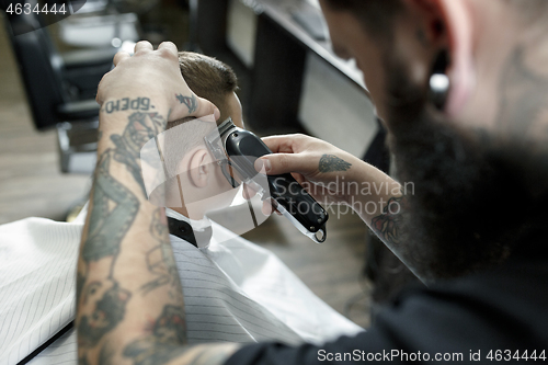 Image of Children hairdresser cutting little boy against a dark background.