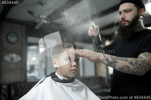 Image of Children hairdresser cutting little boy against a dark background.