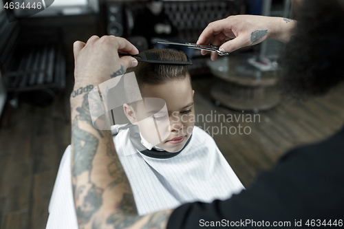 Image of Children hairdresser cutting little boy against a dark background.