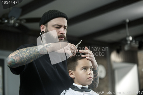 Image of Children hairdresser cutting little boy against a dark background.