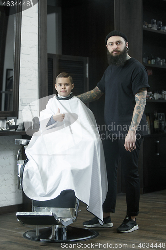 Image of Children hairdresser cutting little boy against a dark background.
