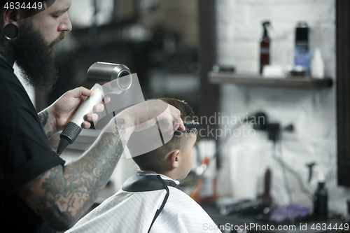 Image of Children hairdresser cutting little boy against a dark background.