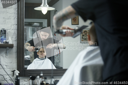 Image of Children hairdresser cutting little boy against a dark background.