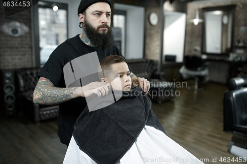 Image of Children hairdresser cutting little boy against a dark background.