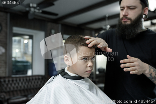 Image of Children hairdresser cutting little boy against a dark background.