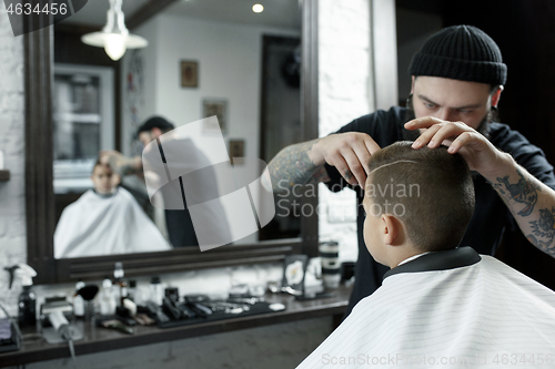 Image of Children hairdresser cutting little boy against a dark background.