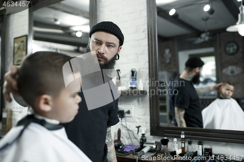 Image of Children hairdresser cutting little boy against a dark background.