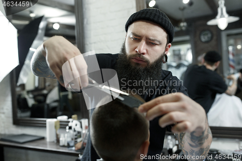 Image of Children hairdresser cutting little boy against a dark background.