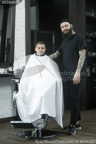 Image of Children hairdresser cutting little boy against a dark background.